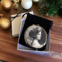 an old photo in a box on a table with christmas decorations and baubles