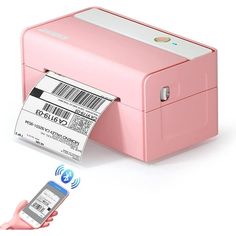 a hand holding a cell phone and a pink printer with a barcode on it