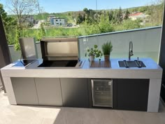 an outdoor kitchen with grill, sink and refrigerator on the outside deck overlooking a city