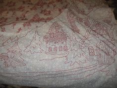 an embroidered blanket with houses and trees on it