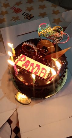 a chocolate birthday cake with lit candles on top