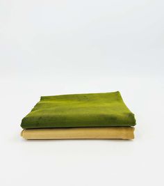 a green cloth covered book sitting on top of a white table