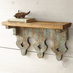 an old wooden shelf with a book on it and a bird figurine sitting on top