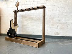 an electric guitar is sitting in a wooden frame on the floor next to a brick wall