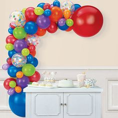 an arch made out of balloons and confetti on a table in front of a wall