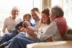 a group of people sitting on a couch with a baby in their lap and smiling at the camera