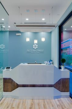 the front desk of an office with blue walls and wood flooring, along with large windows