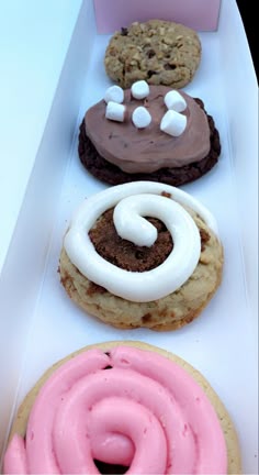 three cookies in a box with frosting and marshmallows