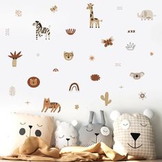 three stuffed animals sitting next to each other in front of a wall with animal decals on it