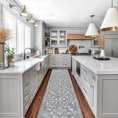 a large kitchen with white cabinets and wood flooring, along with an area rug in the middle