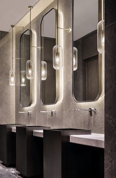 a row of sinks in a public restroom with mirrors on the wall and lights hanging above them