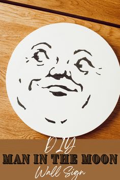 a white plate with a drawing of a man in the moon on it and text overlay that reads diy man in the moon wall sign