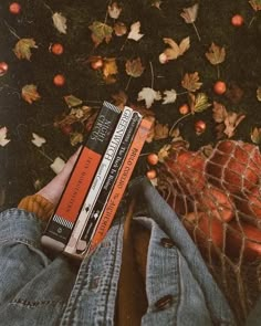 a person is laying on the ground with their legs crossed and holding three books in front of them