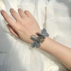 Say goodbye to boring bridesmaid gifts! Our Butterfly Wrist Corsage is the perfect way to show your appreciation while adding a touch of flair to your special day. With its jewel-toned butterfly design and traditional Korean accents, you'll be ready to strut your stuff on the aisle in style! Silver Butterfly Jewelry For Wedding, Silver Bracelet With Butterfly Clasp For Gift, Adjustable Crystal Bracelet For Bridesmaids, Silver Butterfly Knot Jewelry For Party, Silver Bracelets For Wedding Gifts, Silver Jewelry With Butterfly Knot For Party, Party Bangle Charm Bracelet, Elegant Butterfly Charm Bracelet For Parties, Elegant Butterfly Charm Bracelets For Parties