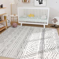 a baby's room with a white crib, rug and animal toys on the floor