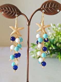 Long cluster earrings made with hard stones, white onyx, blue quartz and turquoise paste pearls, studs with starfish in golden brass, total length 7 cm. Each earring weighs 6 grams. Ocean-inspired Shell Drop Earrings, Adjustable Dangle Earrings Ocean-inspired, Adjustable Shell Earrings, Ocean-inspired, Turquoise Dangle Earrings With Ocean-inspired Style, Turquoise Dangle Earrings Ocean-inspired, Starfish Earrings, White Onyx, Ocean Jewelry, Turquoise Stones