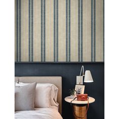 a bedroom with blue and white striped wallpaper on the walls next to a bed