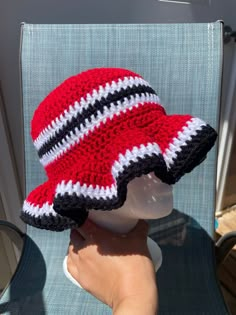 a crocheted red and black hat sitting on top of a white chair