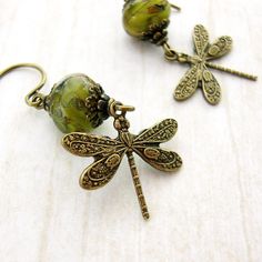 Beautifully detailed brass dragonflies with a Victorian floral motif embossed on the wings dangle from artisan rondelles. These rondelle beads are limited edition, made in small batches by the bead masters in the Czech Republic. They are a swirly mix of opaque beige and transparent green glass with a rustic mottled patina on the surface. The beads are adorned with antiqued brass filigree and caps to enhance the Old-World feel. --------------------------------------------------------------------- Elegant Green Dragonfly Shaped Jewelry, Handmade Green Dragonfly Jewelry, Vintage Handmade Dragonfly Jewelry, Czech Glass Jewelry, Witch Jewelry, Dragonfly Earrings, Nature Inspired Jewelry, Wood Earrings, Jewelry Business