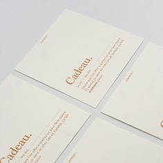 four business cards with gold lettering on them sitting on top of each other in front of a white background