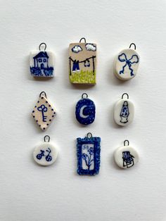 six small ceramic pendants with blue and white designs on them, all in different shapes