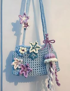 a crocheted bag hanging on the wall with flowers and jellyfishes attached to it