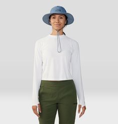 a woman wearing a white shirt and green pants with a blue hat on her head