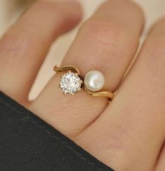 a close up of a person's hand with a pearl and gold ring