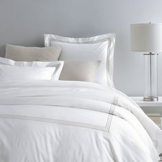 a bed with white sheets and pillows in a room