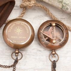 two antique compass key chains are sitting next to an old map