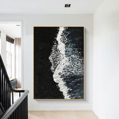 a black and white painting hanging on the wall next to a stair case in a house