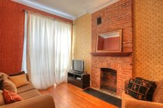 a living room with a brick fireplace and wooden floors