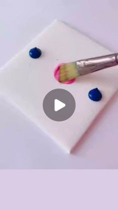 a paintbrush sitting on top of a piece of white paper with blue and pink dots