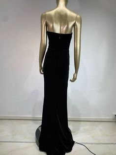 a mannequin wearing a black dress in front of a white wall and floor