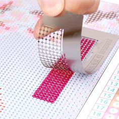 someone is cutting fabric with a pair of scissors on top of the pattern paper that has been cut into squares