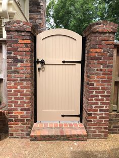 an open door is shown in the middle of a brick fenced entrance to a house