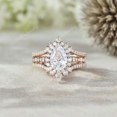 an engagement ring with a pear shaped center surrounded by round brilliant cut diamonds on a textured background