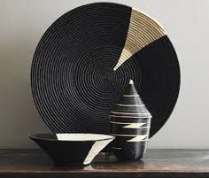 a black and gold plate sitting on top of a wooden table next to a bowl