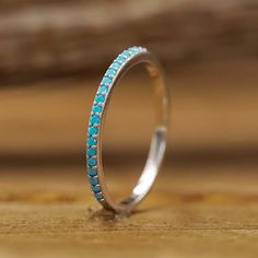 a white gold ring with blue stones on it sitting on a wooden table next to a piece of wood