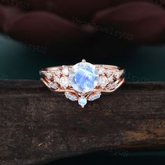 an oval shaped blue topazte and diamond ring on a wooden branch with water in the background