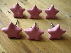 six pink star shaped buttons sitting on top of a wooden table