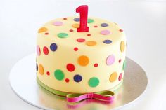 a birthday cake with the number one on it's icing and decorated with polka dots