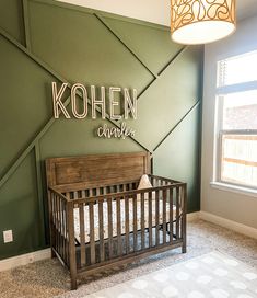 a baby's room with a wooden crib in front of a kohen sign