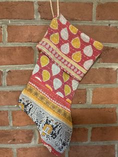 a stocking hanging on a brick wall with an ornament in the middle