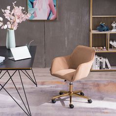 a desk with a chair, laptop and flowers in a vase on the table next to it