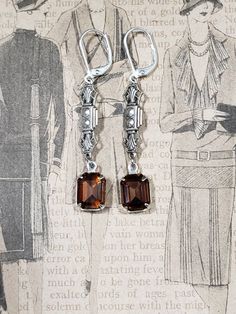 Textured Front, Hollow Back These elegant flapper earrings feature Deco style brass connectors and beautiful smoky topaz (warm brown) glass beads. The antiqued silver brass connectors have a textured front and a hollow reverse side. (SEE 2nd PHOTO) The earrings are extremely lightweight and comfortable to wear; perfect for your next 1920s themed event or everyday. These dainty dangles are 2 inches long and hang from silver plated lever back ear wires. ABOUT THIS COLLECTION What are the three sty Flapper Jewelry, Art Deco Jewelry 1920s, 1920s Earrings, Gold Art Deco Earrings, Teardrop Pearl Earrings, Peach Art, Smoky Topaz, Historical Jewellery, Edwardian Style