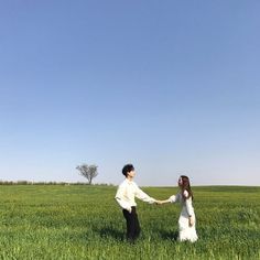 a man and woman holding hands in a field