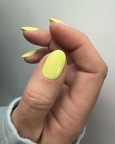 a woman's hand with yellow nail polish holding up her thumb and fingernail