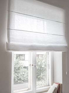 a window with white curtains and books on the windowsill