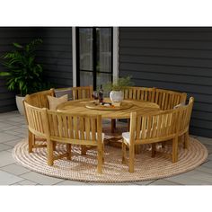 a round wooden table and chairs on a patio with a potted plant in the corner